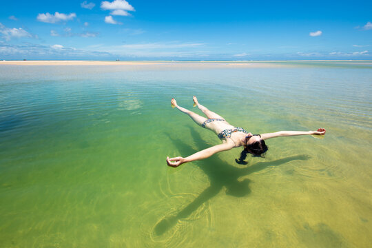 A woman floats in a pool of seawater by the sunny beach on Moreton Island