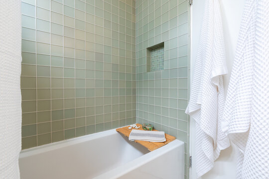 Sleek Bathroom Tub With Blue Green Tile, Spa Tray And White Towels.