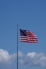 The United States flag waving high in the blue sky