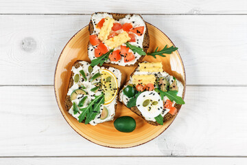 Fototapeta na wymiar Set of open rye bread sandwiches with various fillings. Variety of open sandwiches. Assorted small sandwiches.