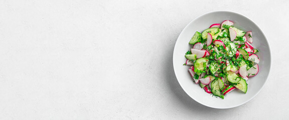Vegetable salad with radish, cucumber and fresh herbs on a light gray background. Top view, copy space.