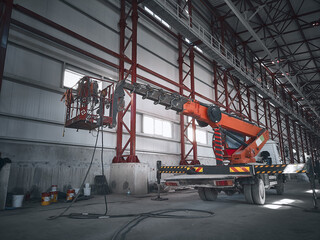 Aerial platform lift. Basket of mobile construction crane inside of industrial building. Telehandler inside of hangar