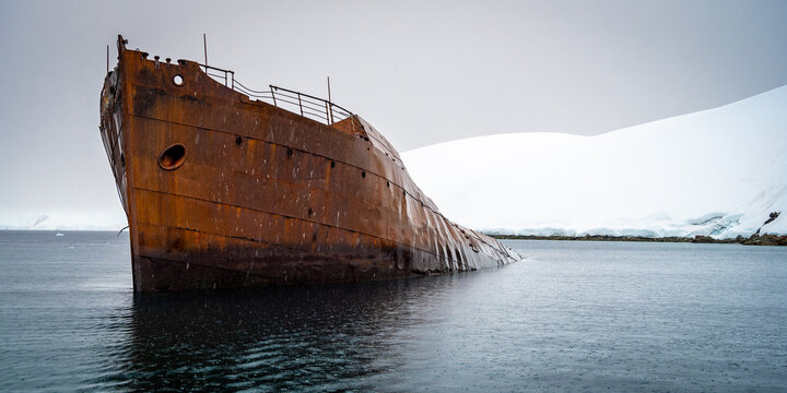 Grounded wreck of Svend Foyn in Antarctica in calm seas and grey sky.