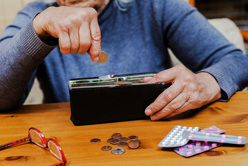 elderly woman holds a purse with money in her hands, counting the last coins to pay for medicines.