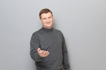 Portrait of friendly mature man stretching one hand to you and smiling
