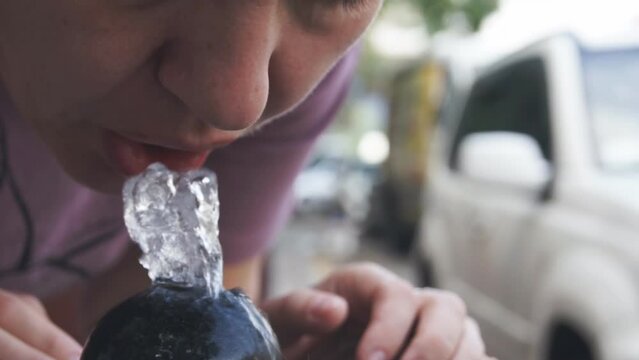 a woman drinks water flowing from a special street spring in the city. Purpulak with clean water. Relief from thirst in hot summer