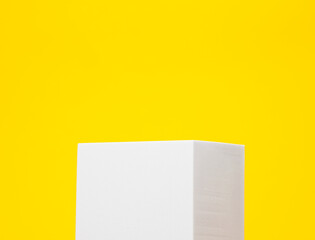 Minimal white podium on a yellow background for product presentation.
