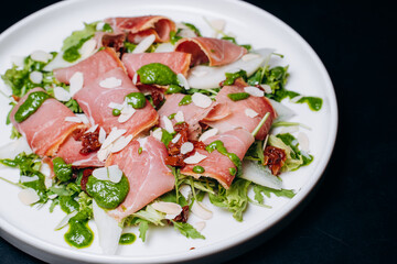 salad with prosciutto and avocado with avocado sauce on a white plate