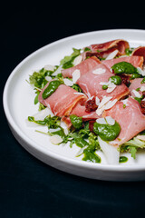 salad with prosciutto and avocado with avocado sauce on a white plate