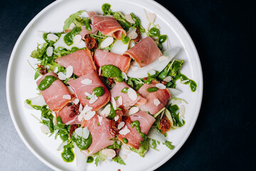 salad with prosciutto and avocado with avocado sauce on a white plate