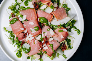 salad with prosciutto and avocado with avocado sauce on a white plate