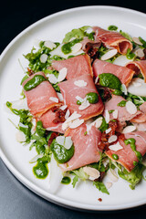 salad with prosciutto and avocado with avocado sauce on a white plate