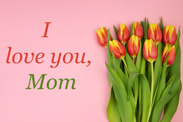 Tulips are yellow-red, on a pink background and red-green text I LOVE YOU MOM. The concept of a greeting card, thanks, invitation, congratulations, happy mother's day, March 8, birthday.