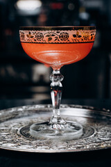 beautiful delicious orange cocktail in an elegant glass on a silver tray different beautiful cocktails in warm colors on a dark background. cocktail or bar menu concept.