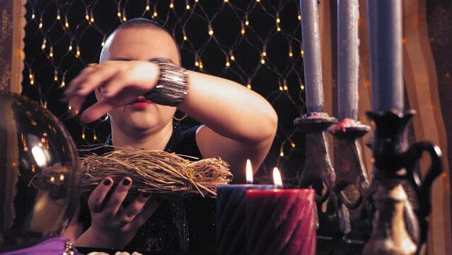 a woman bald fortuneteller is engaged in love magic with herbs in a magic salon, setting fire to them. Overall plan