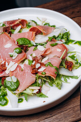 salad with prosciutto and avocado with avocado sauce on a white plate