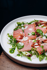 salad with prosciutto and avocado with avocado sauce on a white plate