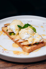 Toast with egg poached, healthy breakfast of waffles, poached egg with bacon and arugula. Brioche sandwich