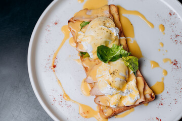 Toast with egg poached, healthy breakfast of waffles, poached egg with bacon and arugula. Brioche sandwich