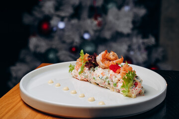 Olivier salad in a white plate in a festive atmosphere. A traditional Russian dish for Christmas and New Year