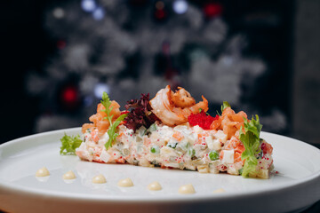 Olivier salad in a white plate in a festive atmosphere. A traditional Russian dish for Christmas and New Year