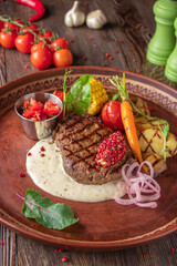 Filet mignon steak served with grilled vegetables, mushrooms and cheese sauce, restaurant dish