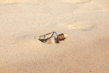 Fototapeta na wymiar Strandgut am Meer Flasche an einem Strand umspült vom Wasser an der Küste.