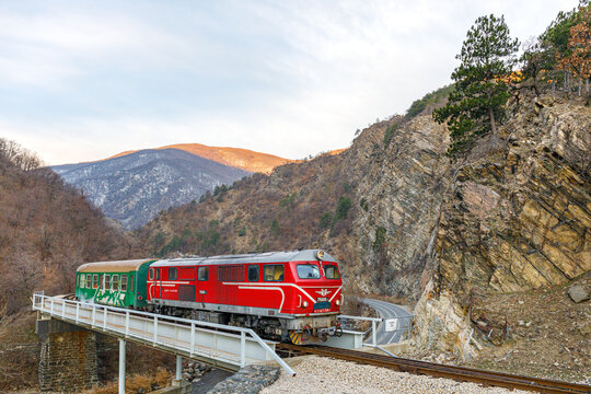red passenger train in the mountains