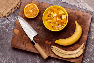 Chopped fruits and Japanese knife on wooden cutting board