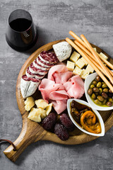 Italian snack and antipasti on a tray and red wine: prosciutto, salami, sun-dried tomatoes, olives, cheese, grissini and dates. Summer snack