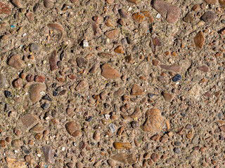 Close-up details of a concrete surface with small gravel pebbles - an abstract textural background