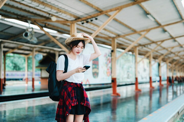 summer, relax, vacation, travel, portrait of beautiful Asian girl using the smartphone mobile to call friends at the train station while waiting for their travel time.