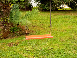 playground swing with no one on it, in a garden