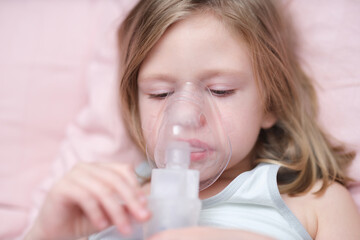 Little sad girl having inhalation for easing cough