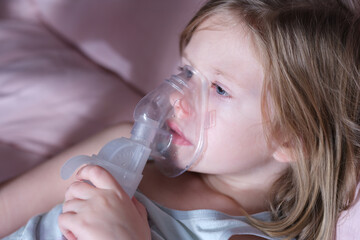 Sick little child in medical oxygen mask lying in bed