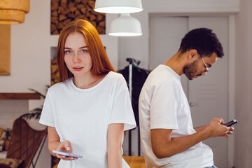 Obraz premium A red-haired girl and her boyfriend sits behind her and uses the phone.