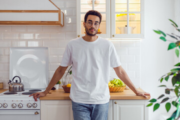 Handsome african american man in white t-shirt standing in the kitchen.