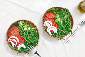 Healthy vegan salad with tomatoes, arugula, avocado, spinach red onion and olive oil. Summer refresh brunch or dinner.