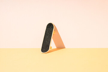 Skateboard leaning against pink wall. Minimal concept.