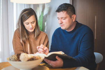 Couple reading bible and pray together at home - 502264441