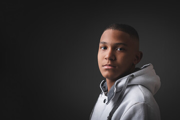Portrait of very serious African-American teenager on a black background.