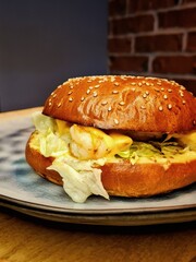 Burger with sesame seeds, herbs and shrimps on a plate