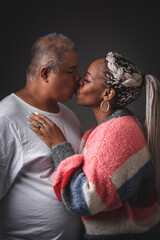 Portrait of heterosexual latin couple kissing on a black background 