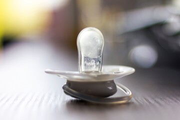 A close up portrait of a soother lying on a wooden table indoor in a living room. The pacifier is...