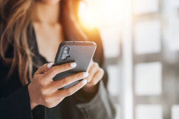 Young businesswoman looking at financial information from a mobile phone, she is checking company financial documents, she is a female executive of a startup company. Concept of financial management.