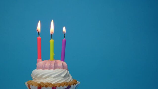 birthday cupcake with lit candle on blue background.Copy space. place for text