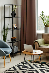 Vertical image of modern living room interior with open laptop by velvet couch