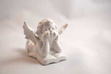 Porcelain angel with a book on a white surface