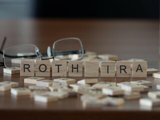 roth ira word or concept represented by wooden letter tiles on a wooden table with glasses and a...
