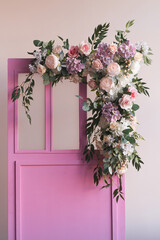 Pink wooden door in vintage style, surrounded on one side by pink roses, peonies, various flowers. With space to copy. High quality photo